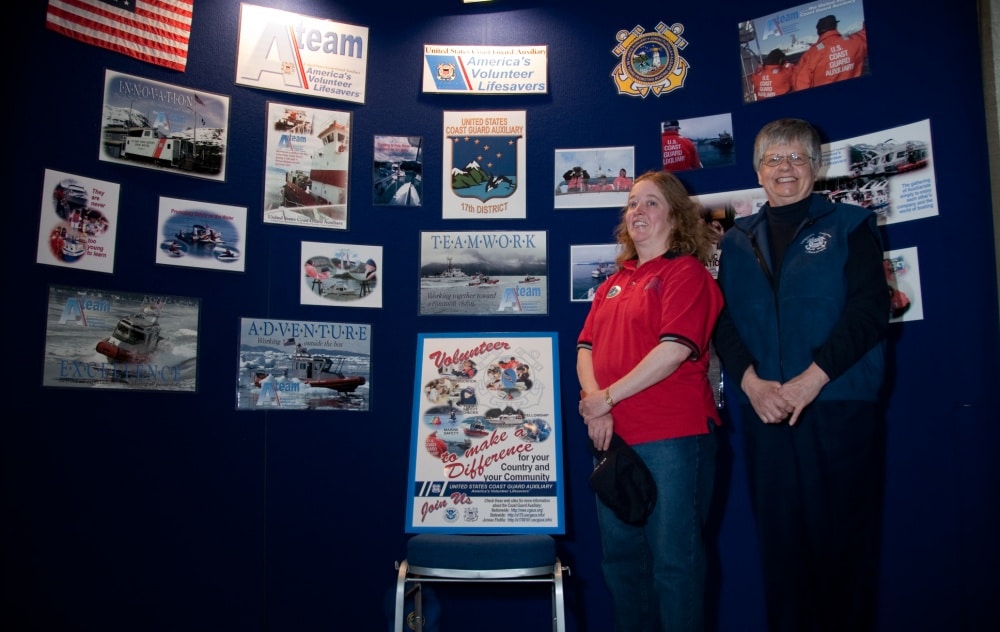two female united states coast guard auxiliary members stand in front of display