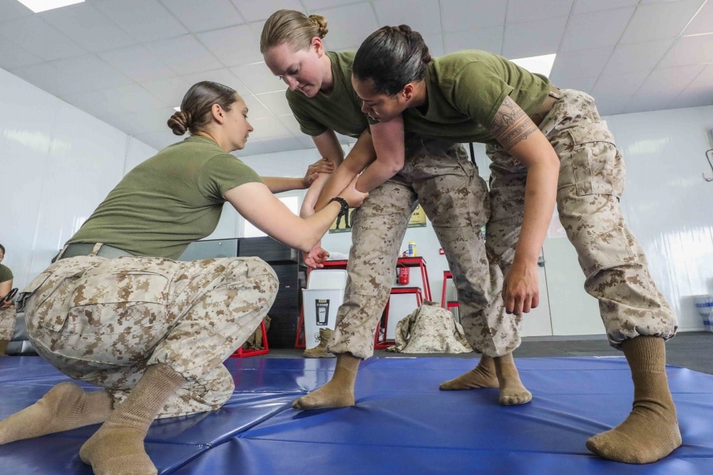 three female marines practice hand to hand combat