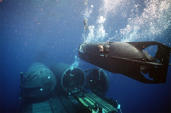 An Mk VIII Mod 1 mini-submarine operated by members of a SEAL Delivery Vehicle Team maneuvers into a dry dock shelter (U.S. Navy).
