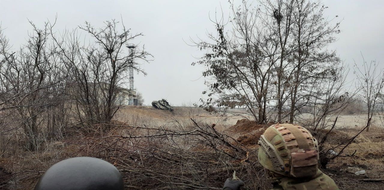 Ukrainian soldiers observe a Russian tank during the Battle of Mariupol