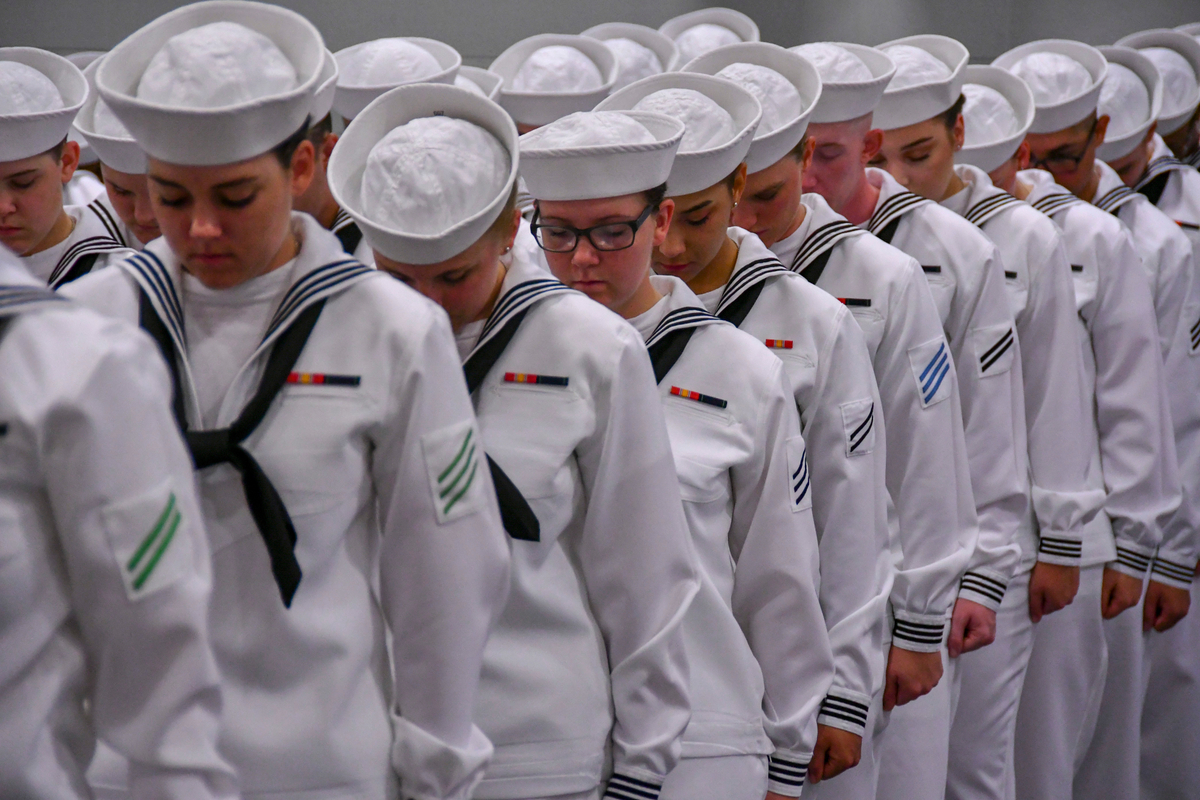 a row of navy recruits bowing their heads