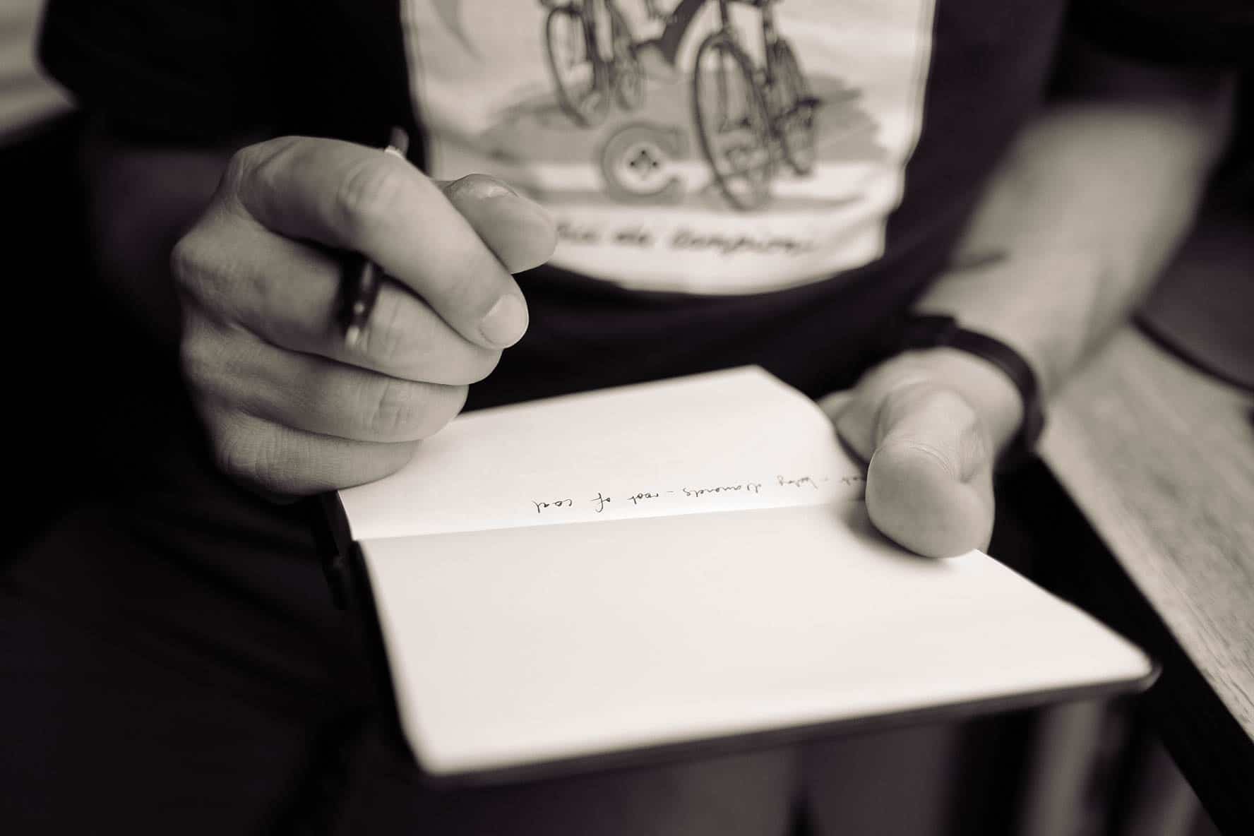 black and white up close picture of hands writing a letter