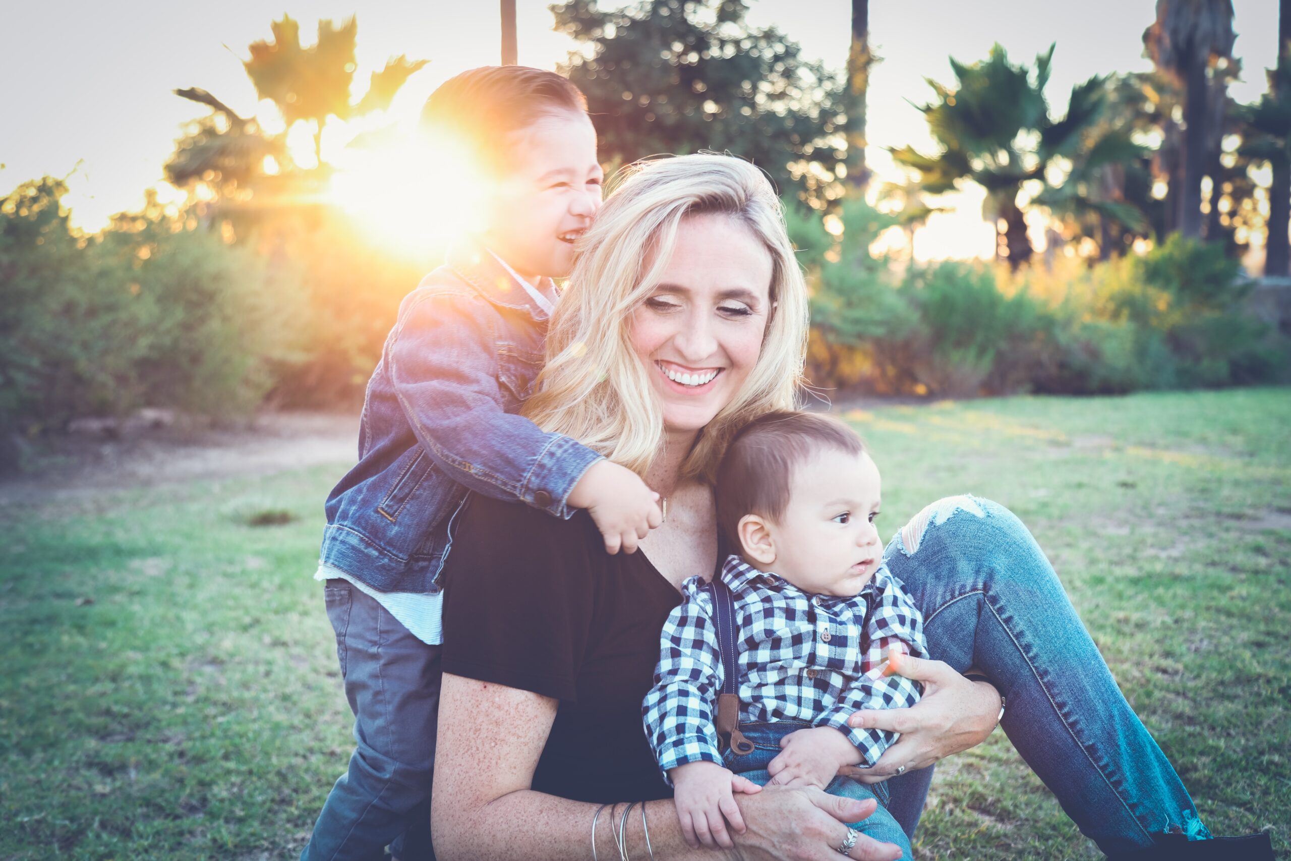 mom smiling with kids in a green yard 