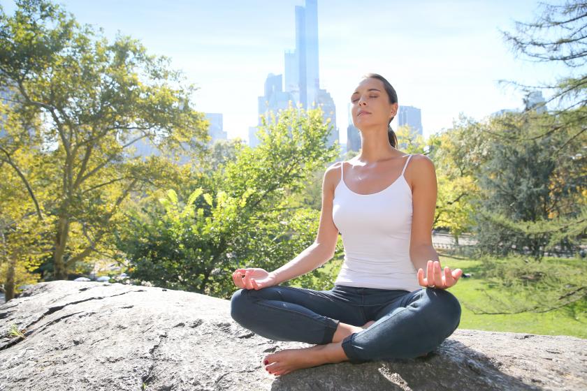 woman meditating on a rock in central park