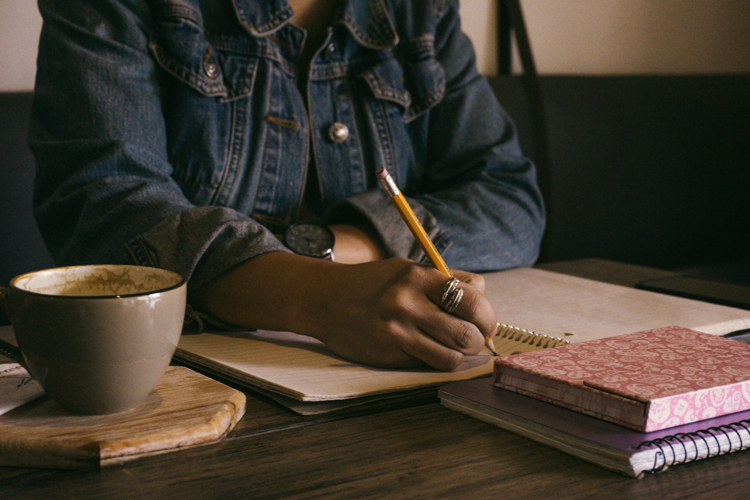 woman writing with a pencil in a spiral notebook