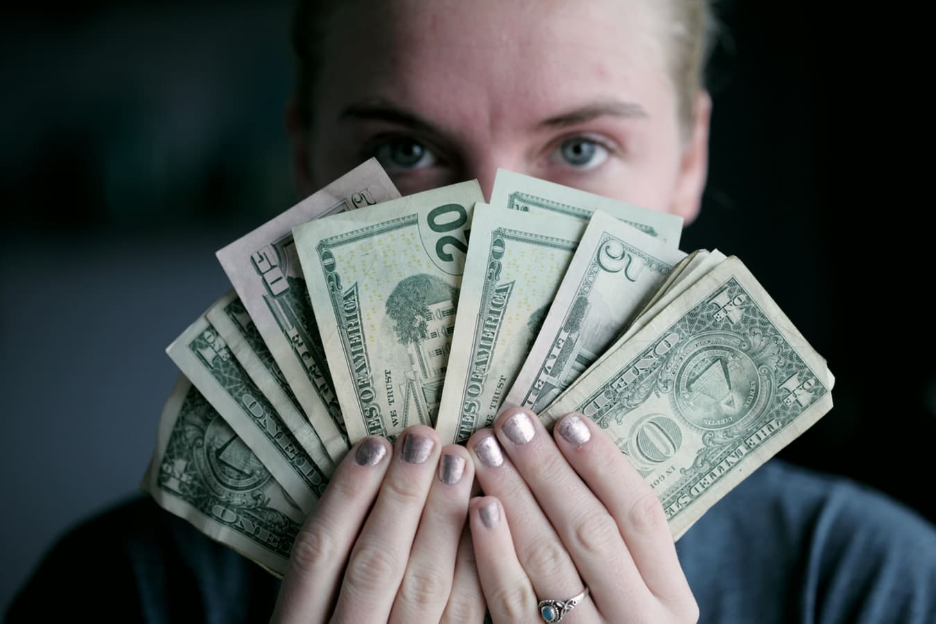 person holding money in front of face